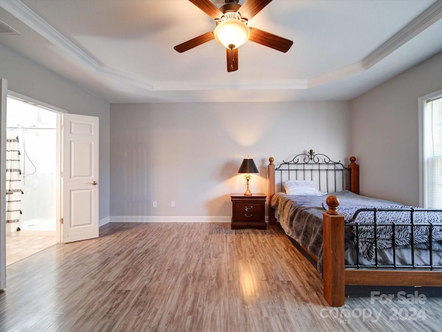 bedroom featuring ceiling fan, wood-type flooring, and a tray ceiling