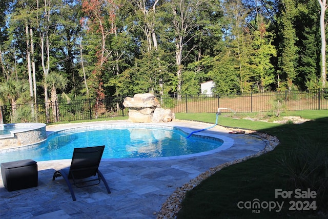 view of swimming pool featuring a lawn, an in ground hot tub, and a patio area