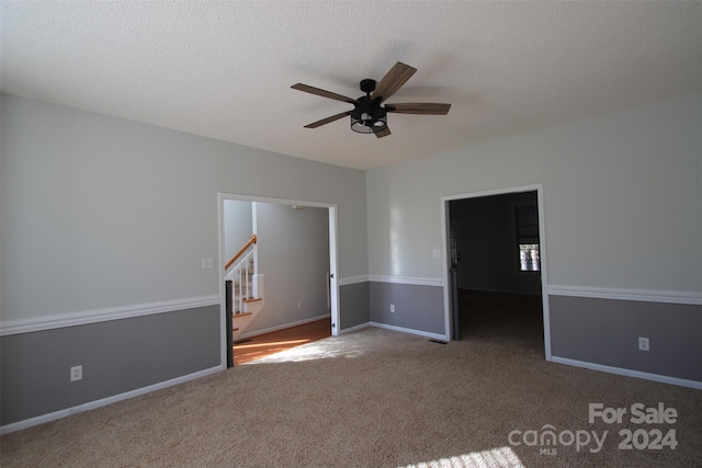 carpeted spare room with ceiling fan and a textured ceiling