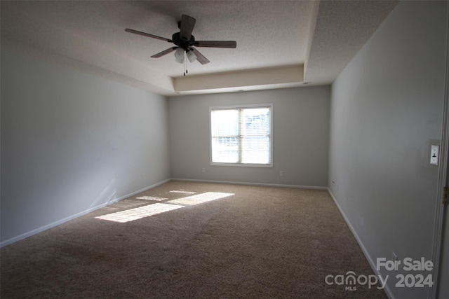 carpeted spare room with ceiling fan, a raised ceiling, and a textured ceiling