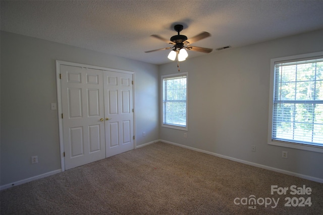 unfurnished bedroom featuring ceiling fan, carpet floors, and multiple windows