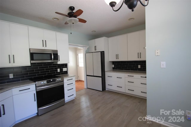 kitchen with light hardwood / wood-style floors, decorative backsplash, ceiling fan, stainless steel appliances, and white cabinets