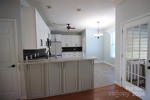 kitchen featuring decorative backsplash, pendant lighting, white cabinets, and dark hardwood / wood-style floors