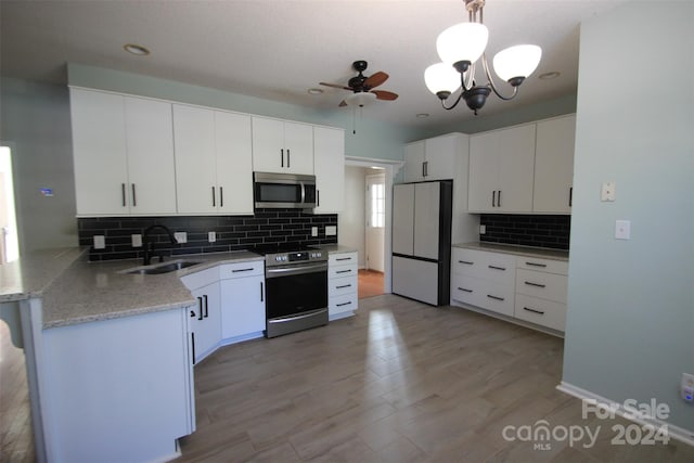 kitchen featuring white cabinets, sink, kitchen peninsula, appliances with stainless steel finishes, and decorative light fixtures