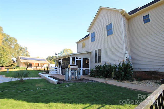 back of house featuring a sunroom and a lawn