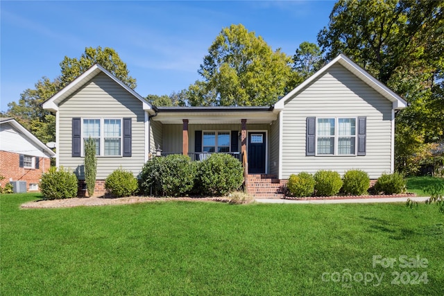 ranch-style home with central air condition unit and a front lawn