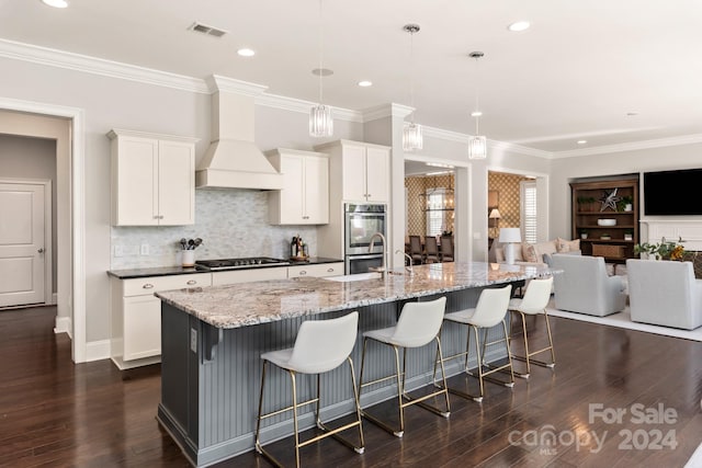 kitchen featuring appliances with stainless steel finishes, a spacious island, decorative light fixtures, white cabinets, and dark wood-type flooring