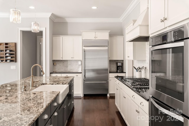 kitchen featuring light stone countertops, white cabinets, pendant lighting, appliances with stainless steel finishes, and dark hardwood / wood-style flooring