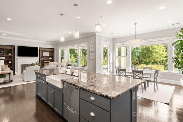 kitchen with decorative light fixtures, a kitchen island with sink, sink, and gray cabinetry