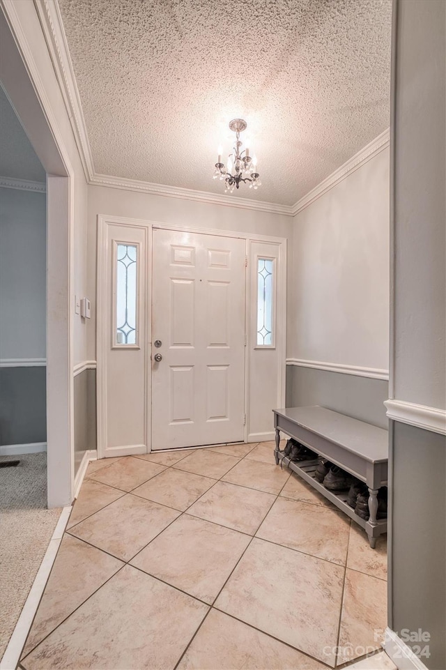 tiled entrance foyer featuring crown molding, a textured ceiling, and a chandelier