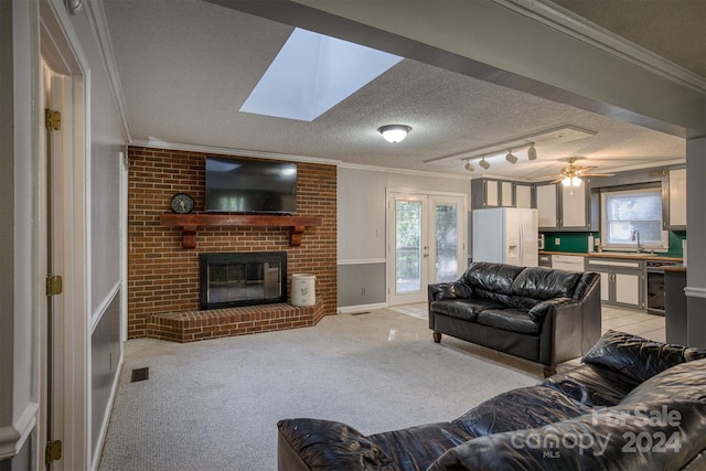 living room featuring track lighting, light carpet, a textured ceiling, and a brick fireplace