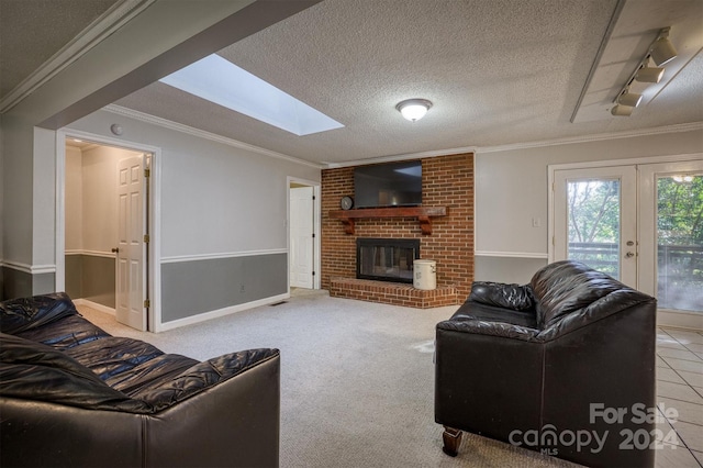 carpeted living room featuring a skylight, french doors, a textured ceiling, a brick fireplace, and ornamental molding