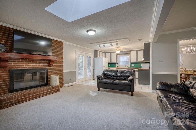 living room with a textured ceiling, a brick fireplace, rail lighting, ornamental molding, and light colored carpet