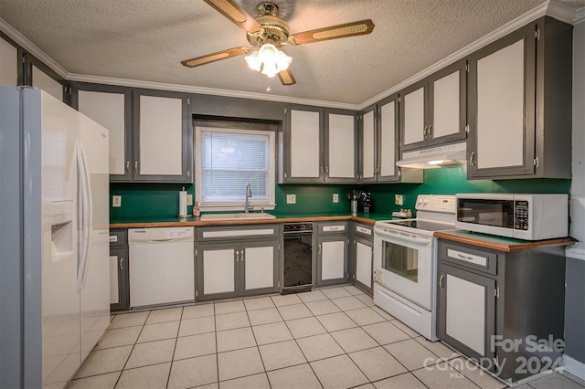 kitchen featuring sink, crown molding, light tile patterned floors, a textured ceiling, and white appliances