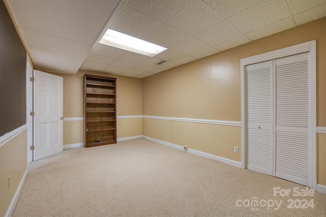 basement featuring carpet flooring and a paneled ceiling