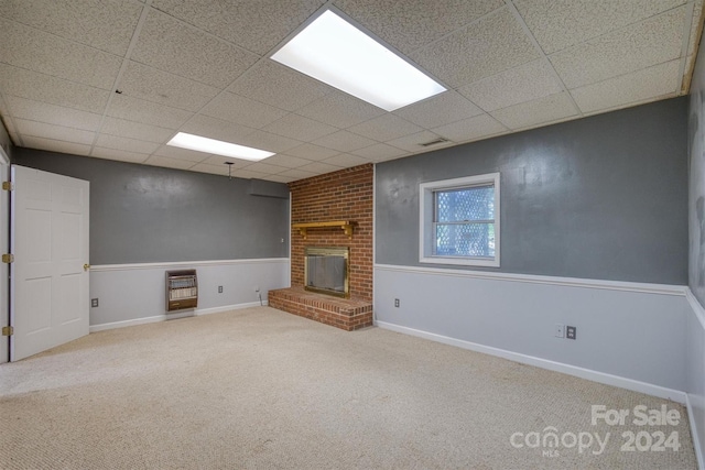 unfurnished living room featuring a brick fireplace, a paneled ceiling, and carpet flooring