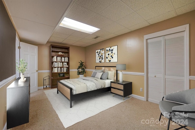 carpeted bedroom featuring a closet and a paneled ceiling