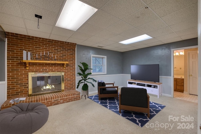 living room with carpet floors, a paneled ceiling, and a fireplace