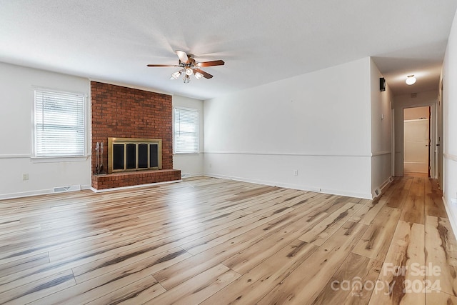 unfurnished living room featuring light wood-type flooring, a healthy amount of sunlight, and a fireplace