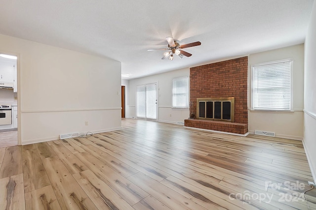 unfurnished living room featuring a fireplace, plenty of natural light, light hardwood / wood-style flooring, and ceiling fan