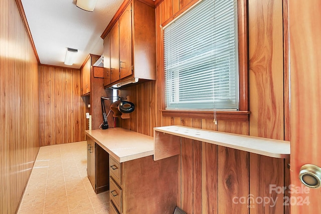 kitchen with built in desk, wood walls, and crown molding