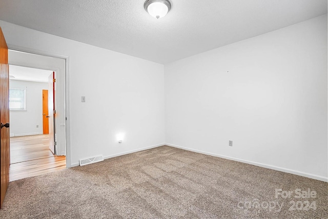 carpeted empty room with a textured ceiling