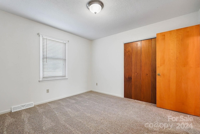 unfurnished bedroom featuring carpet floors, a closet, and a textured ceiling