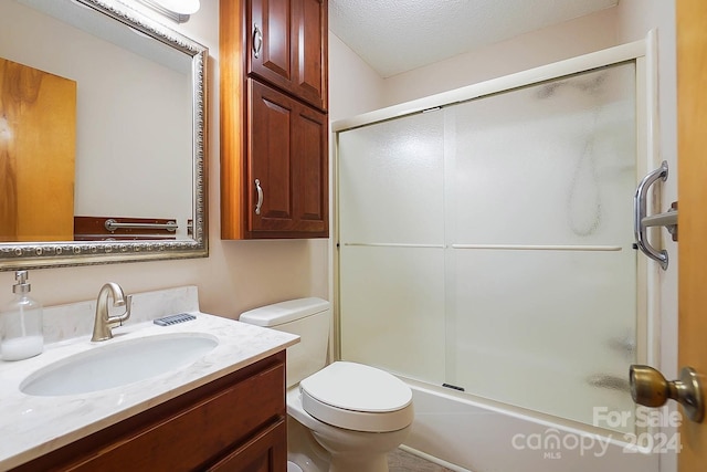 full bathroom featuring bath / shower combo with glass door, vanity, toilet, and a textured ceiling