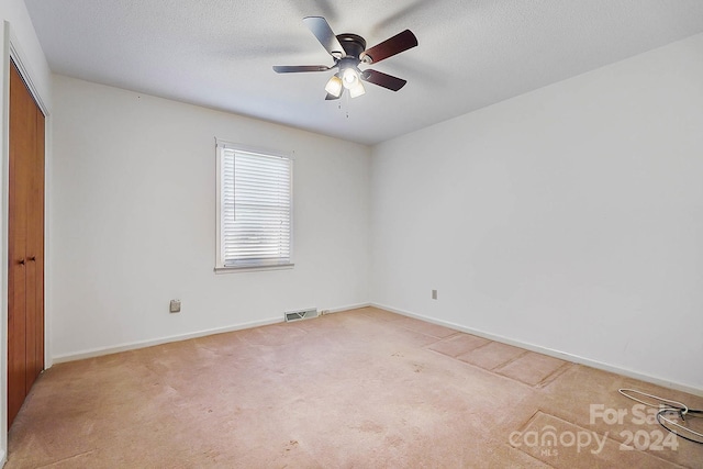 unfurnished room featuring light carpet, ceiling fan, and a textured ceiling