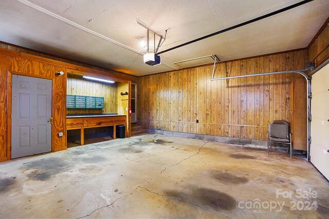 garage featuring a garage door opener, wood walls, and a workshop area