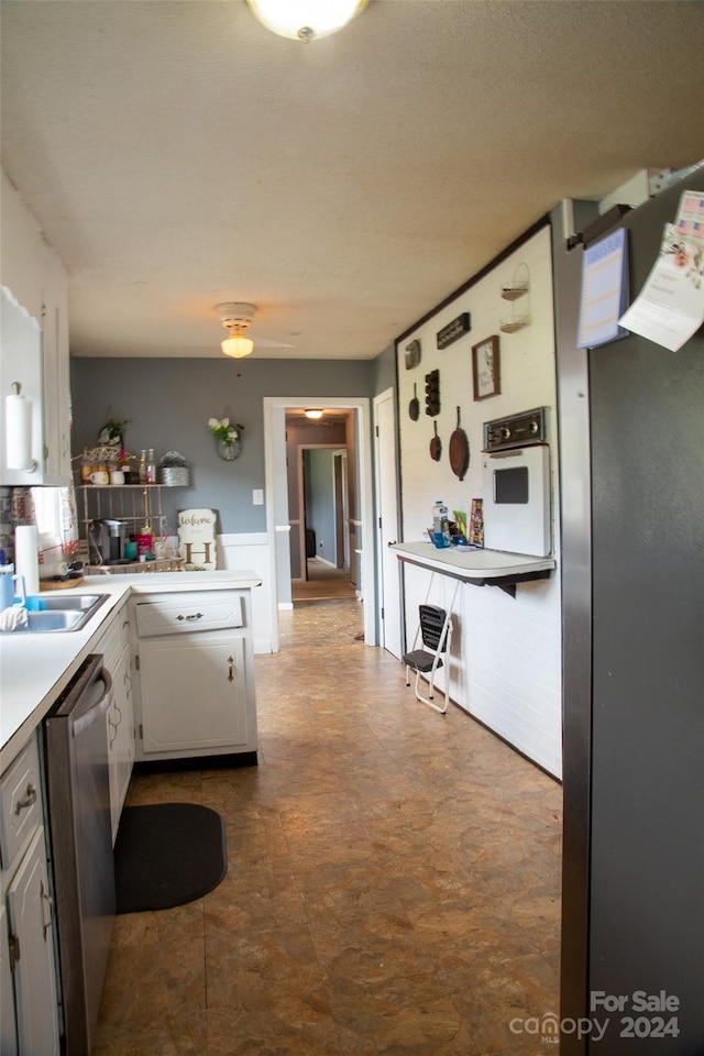 kitchen with white oven, sink, kitchen peninsula, white cabinets, and stainless steel dishwasher