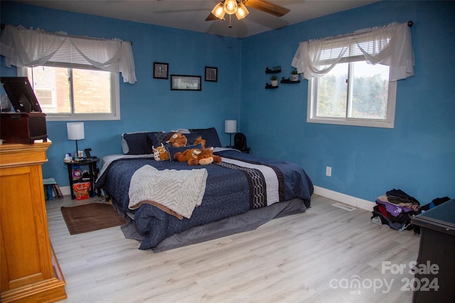 bedroom with light hardwood / wood-style floors, multiple windows, and ceiling fan