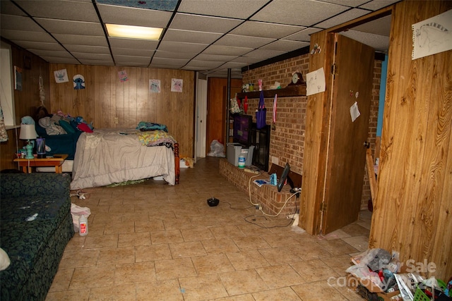 bedroom featuring a drop ceiling and wood walls