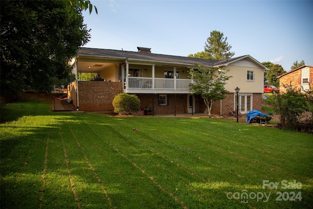 back of property with a yard and a balcony