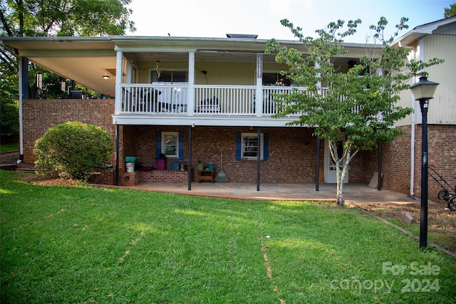 rear view of house with a patio, a balcony, and a lawn