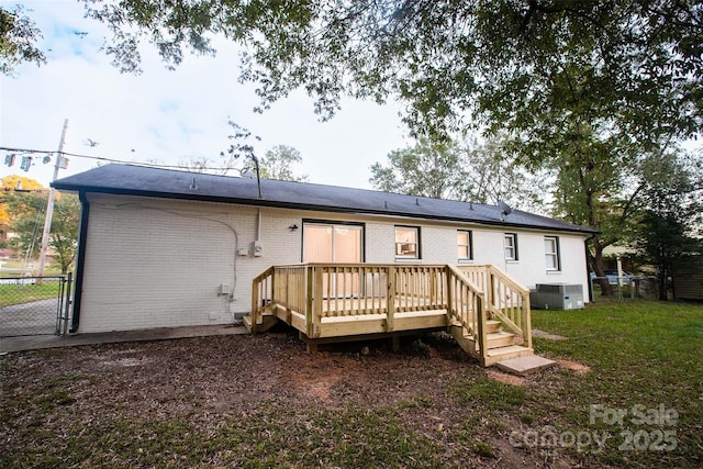 rear view of property featuring central air condition unit, a yard, and a wooden deck