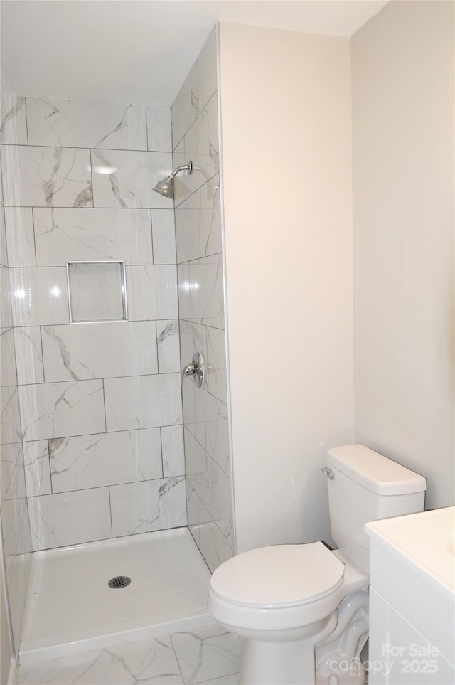 bathroom with vanity, toilet, and tiled shower