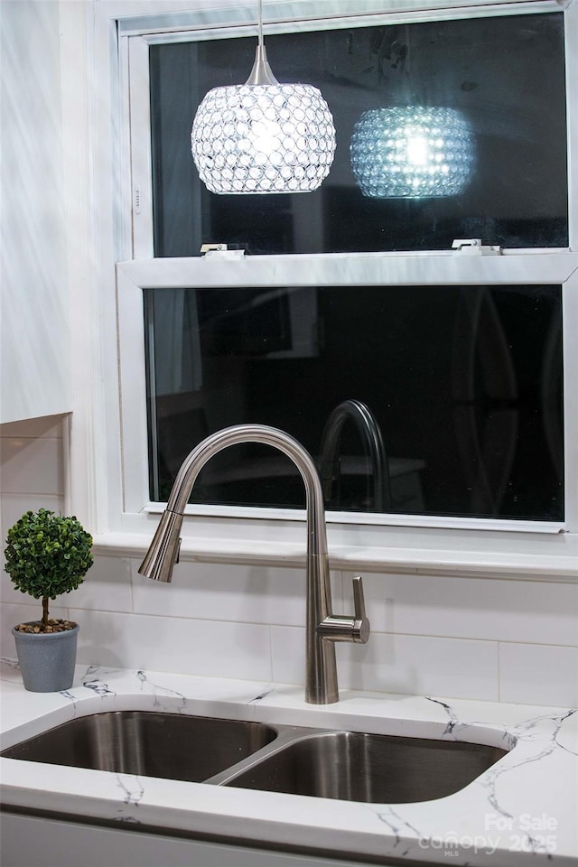 details with light stone counters, sink, and hanging light fixtures