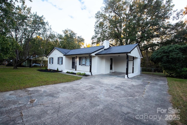 ranch-style home featuring a front lawn and a carport
