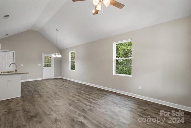 unfurnished living room featuring ceiling fan with notable chandelier, lofted ceiling, dark wood-type flooring, and a wealth of natural light