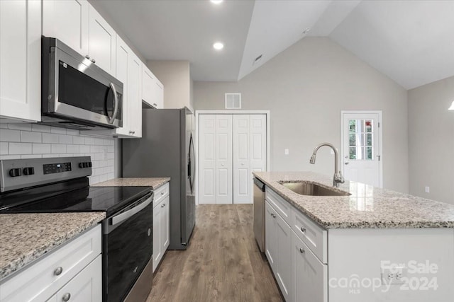 kitchen featuring hardwood / wood-style floors, sink, white cabinetry, appliances with stainless steel finishes, and a center island with sink