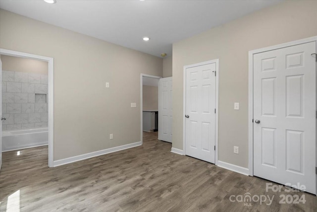 unfurnished bedroom featuring wood-type flooring and connected bathroom