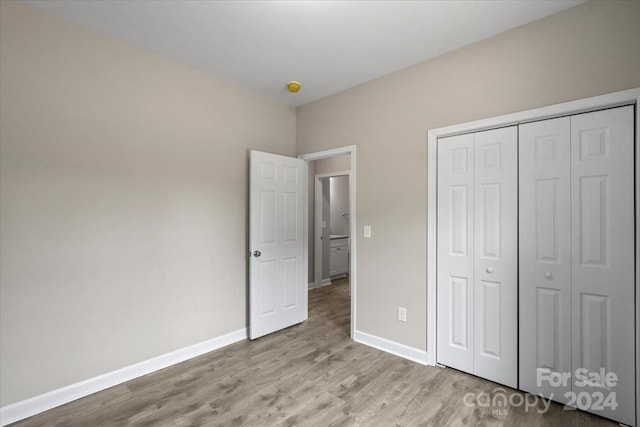 unfurnished bedroom with light wood-type flooring and a closet