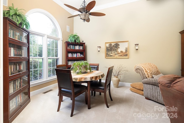 carpeted dining room featuring ornamental molding, plenty of natural light, and ceiling fan