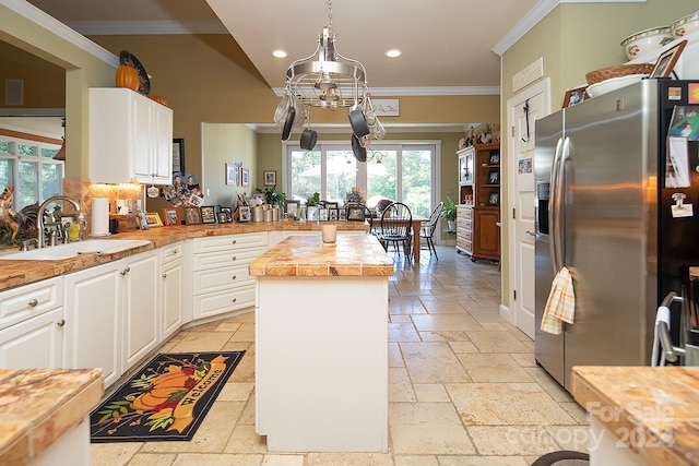 kitchen with sink, ornamental molding, stainless steel fridge with ice dispenser, and white cabinets