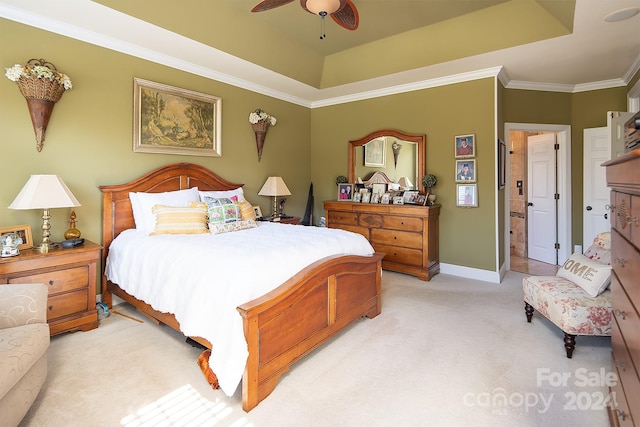 bedroom featuring ensuite bath, crown molding, light colored carpet, a raised ceiling, and ceiling fan