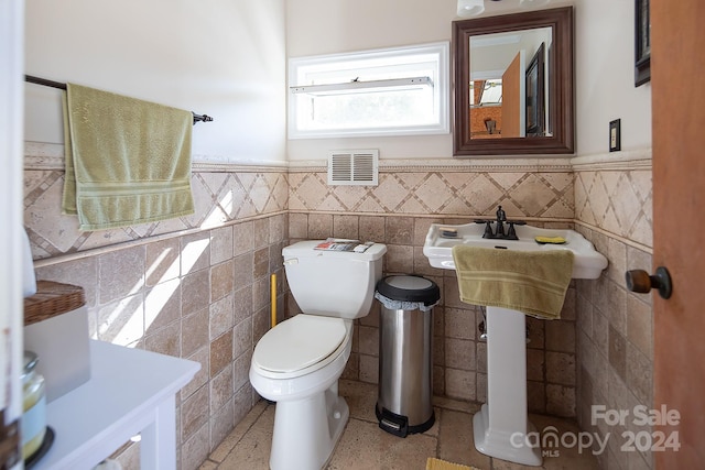 bathroom featuring toilet and tile walls