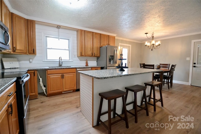 kitchen with a kitchen island, light hardwood / wood-style flooring, stainless steel appliances, sink, and pendant lighting