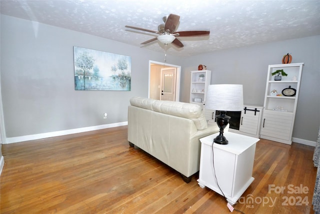 living room with a textured ceiling, wood-type flooring, and ceiling fan