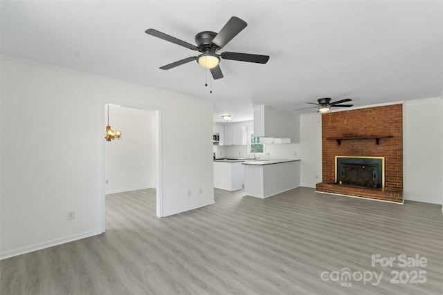 unfurnished living room with a brick fireplace, light wood-type flooring, baseboards, and ornamental molding